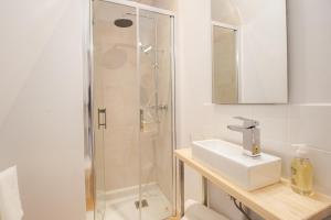 a white bathroom with a shower and a sink at LE COURSARLON in Bourges