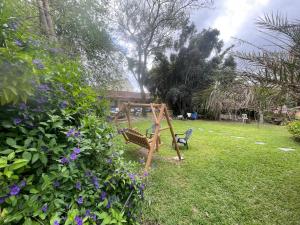 a swing set in a yard with purple flowers at Gross Nofesh and Spa Guesthouse in Beit Hillel
