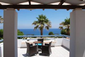 un patio con tavolo, sedie e vista sull'oceano di Aithrio Hotel a Niforeika