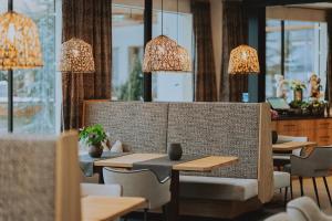 un restaurante con mesas, sillas y lámparas de araña en Familienresort Buchau, en Maurach
