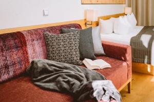 a person laying on a couch with a book at Familienresort Buchau in Maurach