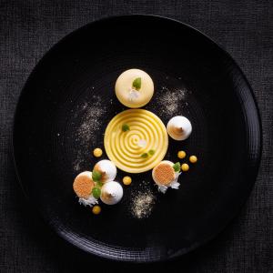 a black plate with a yellow dessert on it at Hotel SPA Restaurant Husseren Collections - Proche Colmar - Eguisheim in Eguisheim +110 photos