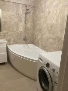 uma casa de banho com uma banheira e uma máquina de lavar roupa em Lovely 2-bedroom apartment in Chisinau centre em Chisinau
