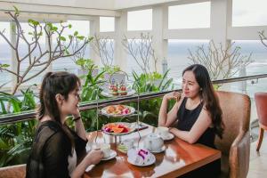 two women sitting at a table in a restaurant at Paris Deli Danang Beach Hotel in Danang