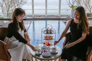two women sitting at a table with a plate of food at Paris Deli Danang Beach Hotel in Danang +37 photos