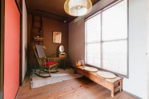a room with a large window with a bench and a chair at TSUDOYA 天王寺 in Osaka