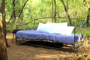 Cama de metal con almohadas blancas sentadas en el bosque en Ndlovu Tiny Home Dinokeng en Klipdrift