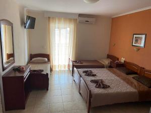 a hotel room with two beds and a window at Hotel Manos in Paralia Katerinis