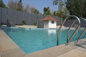 a swimming pool with a small house in front of a fence at Anamala Serenity Homestay Kerala in Lakkidi