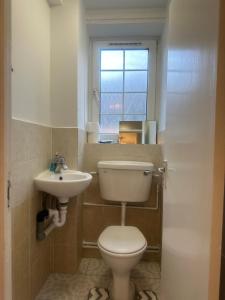 a bathroom with a toilet and a sink and a window at Holybush Bethnal Green in London