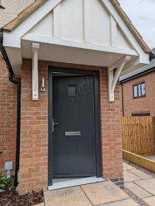 a black front door of a brick house at Immaculate 1-Bed Apartment in Hinckley in Hinckley