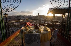 a table on a balcony with a view of a city at Riad El Bacha in Fès