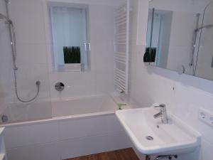 ein weißes Badezimmer mit einem Waschbecken und einer Badewanne in der Unterkunft Ferienwohnungen Neukirchen in Neukirchen am Teisenberg
