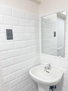 a white bathroom with a sink and a mirror at Ba-lai homes in Baguio