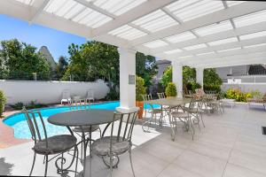 eine Terrasse mit Tischen und Stühlen und einem Pool in der Unterkunft Morningside Cottage in Tokai