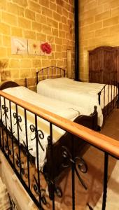 two twin beds in a bedroom with a brick wall at Il Mithna farmhouse with indoor heated jacuzzi pool in Għarb