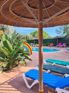 a pool with a umbrella and lounge chairs and a rainbow at Camping la Croix du Sud in Saint-Tropez