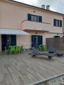 ポルトフェッラーイオにあるRESIDENCE TERME ISOLA D'ELBA SRLの緑の椅子とテーブル付きのパティオ、建物