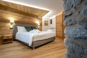 een slaapkamer met een bed en een stenen muur bij Les Plaisirs d'Antan in Aosta