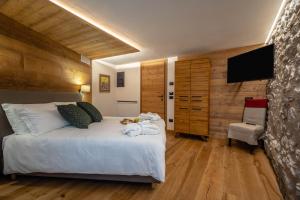 a bedroom with a bed with a television and a chair at Les Plaisirs d'Antan in Aosta