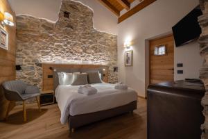 sypialnia z dużym łóżkiem i kamienną ścianą w obiekcie Les Plaisirs d'Antan w Aoście