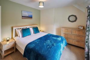 a bedroom with a bed with blue sheets and a dresser at Host & Stay - Melody's Cottage in Belford