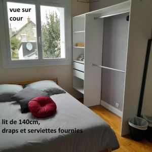 um quarto com uma cama com uma almofada vermelha em chambre dans une colocation em Rennes