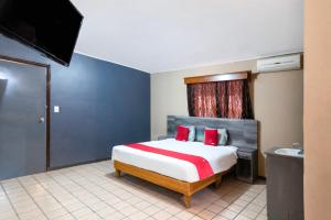 1 dormitorio con 1 cama grande con almohadas rojas en OYO Hotel Real Del Sur, Estadio Chihuahua, en Chihuahua