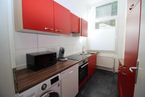 una pequeña cocina con armarios rojos y microondas en Apartment with terrace in Wuppertal, en Wuppertal