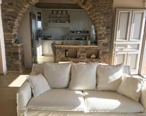 a white couch in a living room with a kitchen at Cycladic house with panoramic view in Ktikádhos