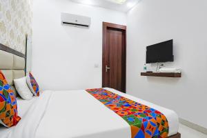 a white bedroom with a bed and a tv at FabHotel Swess in Agra