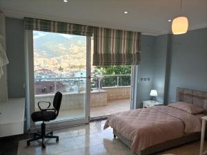 ein Schlafzimmer mit einem Bett und einem Stuhl sowie einem großen Fenster in der Unterkunft modern house in perfect location in Alanya