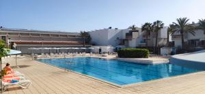 a large swimming pool with chairs and a building at SIMPLE Apartment Frontera Primavera POOL in South TENERIFE in Costa Del Silencio