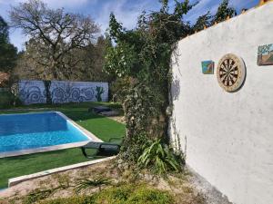 a tree next to a wall with a swimming pool at A casinha in Vila Nova de Anços