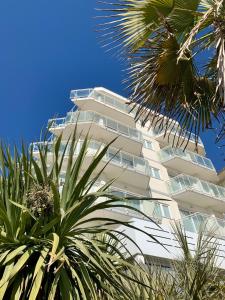 un alto edificio bianco con palme di fronte di Hotel Nizza Frontemare Superior 3 Stelle a Lido di Jesolo