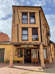 Albergue hostal Sahagún في ساهاجون: مبنى من الطوب الطويل به نوافذ وباب