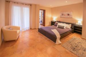 a large bedroom with a bed and a chair at Villa Es Figueral in Campos +48 photos