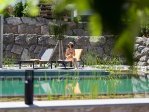 una mujer sentada en un piano junto a una piscina en Hotel Gänsleit, en Söll