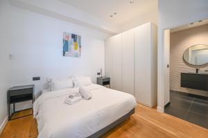 a white bedroom with a white bed and a mirror at Appartement de Prestige - Grand Varenne in Paris