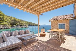 eine Terrasse mit Sofa, Tisch und Wasser in der Unterkunft La Villa Bleue Secluded Hvar Beach House in Zastražišće