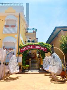 a hotel with chairs in front of a building at Meublè Tripoli in Grado