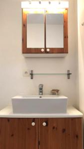 a bathroom sink with a wooden cabinet and a mirror at Le Hameau des Sources by Ateya in Montbrun-les-Bains
