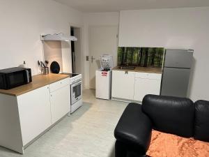 una cucina con mobili bianchi e una sedia in pelle nera di 2 Zimmer Whg a Langelsheim