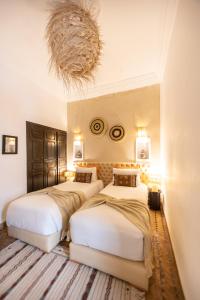 three beds in a room with a chandelier at Riad Baba Ali in Marrakesh