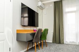 a kitchen with a desk and two green chairs at Dosman Hotel Bishkek in Bishkek