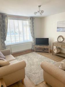 a living room with a couch and a television at Wayside, Yorkshire Wolds Holiday Home in Nafferton