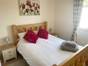a bedroom with a bed with two red pillows at Wayside, Yorkshire Wolds Holiday Home in Nafferton