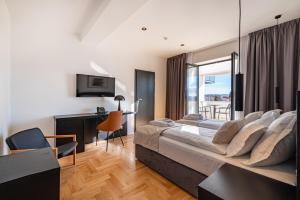 a bedroom with a bed and a desk and a television at Miramare Hotel in Zadar