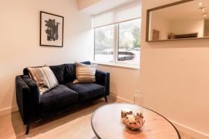 a living room with a black couch and a glass table at Redhill Apartments by Pay As U Stay in Redhill