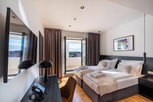 a bedroom with a bed and a desk with a phone at Miramare Hotel in Zadar